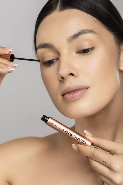 Woman applying QUALASH Advanced Eyelash Serum to her upper lash line